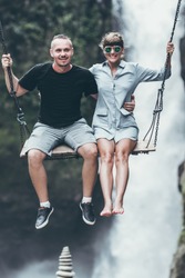 Young honeymoon couple swings in the jungle near the waterfall, Bali island, Indonesia. Ubud.