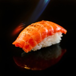 Close up scorched nigiri in a flame of fire, burn on salmon and wagyu sushi, japanese cuisine.