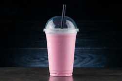 Diet Food and healthy nutrition. Pink Fruit smoothie, cherry milkshake in plastic glass on a dark background. cherry milkshake in takeaway cup