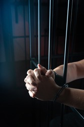 Handcuff on man's arms, praying for forgiveness in Church. prisoner in handcuffs praying, prisoner prays in a cell behind bars