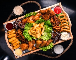 Large beer plate, large set of beer snacks. assorted snacks deep-fried beer. Food for a holiday for a large company. hot meat snacks for beer served on wooden dish board top view, flat lay
