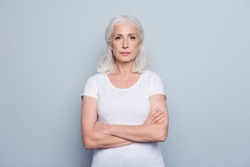Portrait  of nice, charming, aged, perfect, nice, pretty, concentrated, woman with folded hands, serious expression, looking at camera,  standing over gray background