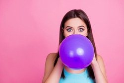 It's difficult! Portrait of beautiful adorable charming attractive woman dressed in blue casual t-shirt, blowing big ultraviolet balloon, isolated on bright vivid pink background