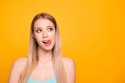 Portrait of foolish cute straight-haired blonde caucasian girl, showing tongue out. Copy space, isolated over yellow background