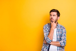 Close up portrait of thoughtful man who looks away touching his chin and weighs the pluses and minuses of the offer isolated on bright yellow background with copy space for text