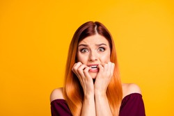 Portrait of red straight-haired attractive cute nice scared worried young girl, biting nails. Isolated over bright vivid yellow background