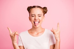Close up portrait of punk lady in casual wear isolated on shine pink background show tongue out, close eyes and make horns by fingers
