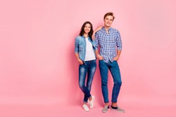 Full length body size photo of standing confident she her he him his pair in relaxed pose hands in pockets close casual jeans denim shirts plaid shirts isolated on rose background