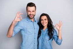 Close up portrait two amazing she her he him his couple lady guy couple stand close hold hands arms show okey symbol wear casual jeans denim shirts outfit clothes isolated light grey background