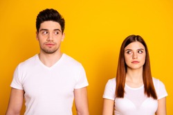 Close up photo two amazing beautiful she her he him his couple standing side by side look each other not smile tell talk speak say wear casual white t-shirts outfit clothes isolated yellow background