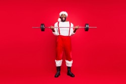 Full length photo of excited santa claus in xmas headwear hat holding sportive equipment screaming wow omg wearing white jumper pants trousers isolated over red background