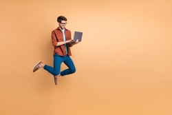 Full length body size view of his he nice attractive cheerful cheery successful brunet guy jumping in air using laptop home-based job isolated over beige color pastel background