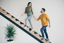 Let's explore this place! Full size profile photo of handsome guy and his pretty lady walking to bedroom go up stairs in just bought modern flat indoors wear casual clothes