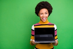 Portrait of positive afro american girl hold netbook show touch screen recommend digital modern technology wear casual style clothes isolated over green color background