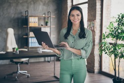 Photo of attractive latin business lady hold notebook chatting colleagues read report meet partners friendly person wear striped shirt green pants stand modern interior office indoors