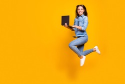 Full length profile photo of funny business lady jump high up hold notebook hands addicted worker always online wear casual denim outfit white sneakers isolated yellow color background