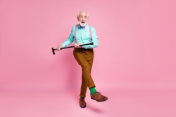 Full length photo of active grandpa moving dance pensioner party use walk stick raise leg wear mint shirt suspenders bow tie pants shoes green socks isolated pink pastel background