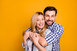 Photo beautiful wife lady handsome husband guy couple hugging good mood in love perfect pair hold arms wear casual shirts clothes isolated yellow color background
