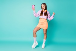 Full body photo of attractive lady hold coffee mug listen modern technology earphones dance tender moves wear violet sweater orange skirt shoes socks isolated teal color background