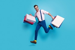 Full length profile photo of handsome business man carry bags jump high buy vacation stuff shopping center store mall wear specs shirt suspenders pants boots isolated blue color background