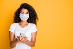Portrait of her she attractive healthy wavy-haired girl wearing safety mask using gadget reading news mers cov pathogen influenza cases blog service copy space isolated vivid yellow color background