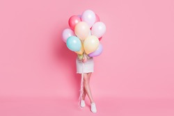 Full size photo of funny lady come birthday party hold many air balloons hiding face surprise visit wear casual green crop pullover jeans skirt shoes isolated pink pastel color background