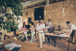 Nice confident experienced people director calling employee discussing document analysis at modern industrial loft brick open space style interior workplace workstation
