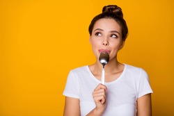 Portrait of positive inspired girl hipster lick lips spoon look copyspace feel interested about what she will eat breakfast wear white t-shirt isolated over bright shine yellow color background