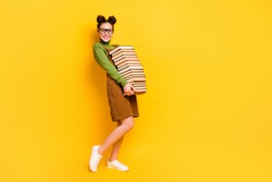 Full length body size profile side view of her she attractive cheerful cheery strong knowledgeable girl carrying book delivery isolated bright vivid shine vibrant yellow color background