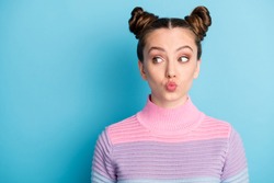 Closeup photo of attractive teen lady two funny buns good mood charming cute nice youngster look side empty space sending air kisses wear casual warm sweater isolated blue color background