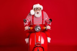 Portrait of his he handsome amazed impressed bearded Santa father riding moped delivering gifts tradition journey fast speed hurry rush isolated bright vivid shine vibrant red color background