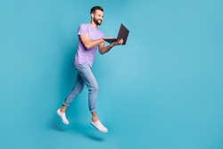 Full length body size photo of cheerful jumping man working on laptop doing project isolated on vivid blue color background