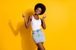 Portrait of pretty cheerful wavy-haired lady showing double v-sign having fun isolated over shine yellow color background