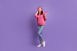 Full length body size photo of girl in headphones enjoying music holding cellphone isolated on vivid violet color background