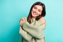 Photo portrait of smiling girl hugging self isolated on vivid cyan colored background