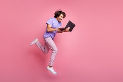 Full size profile photo of brown haired bristled trendy stylish man jump run hold laptop wear violet t-shirt isolated on pink color background