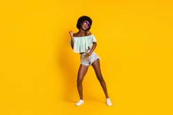 Full length body size photo of black skinned woman dancing on weekend wearing star shaped sunglass isolated on vibrant yellow color background