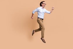 Full length profile photo of guy jump run excited wear eyewear shirt pants shoes isolated beige color background