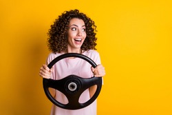Photo portrait of female driver keeping steering wheel staring at blank space isolated on vivid yellow color background