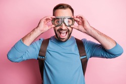 Photo of impressed young man dressed blue sweater arms eyewear rucksack ready jump parachute isolated pink color background