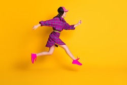 Full length profile portrait of attractive lady running headwear magenta outfit isolated on yellow color background