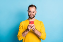 Photo of young unhappy upset sad unsure uncertain man see dislike bad comment in phone isolated on yellow color background