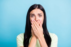Photo portrait of scared woman covering mouth with two hands isolated on pastel blue colored background