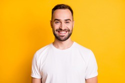Portrait of attractive cheerful bearded guy freelancer wearing white tshirt isolated over bright yellow color background