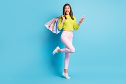 Photo portrait full body view of woman standing on one leg holding phone shopping bags isolated on pastel blue colored background
