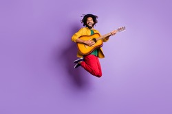 Full length photo of funky dark skin man wear yellow shirt jumping playing guitar isolated violet color background