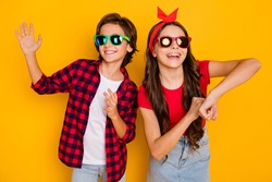 Photo of two funky kids dance having fun wear sunglass casual clothes isolated yellow color background