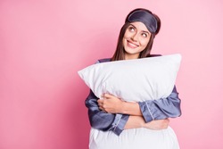 Photo portrait of dreamy girl hugging pillow looking at blank space isolated on pastel pink colored background