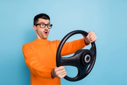 Photo of young man amazes shocked surprised drive auto hold steering-wheel look empty space isolated over blue color background