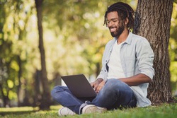 Photo portrait of man in glasses smiling sitting in green park working on laptop smiling